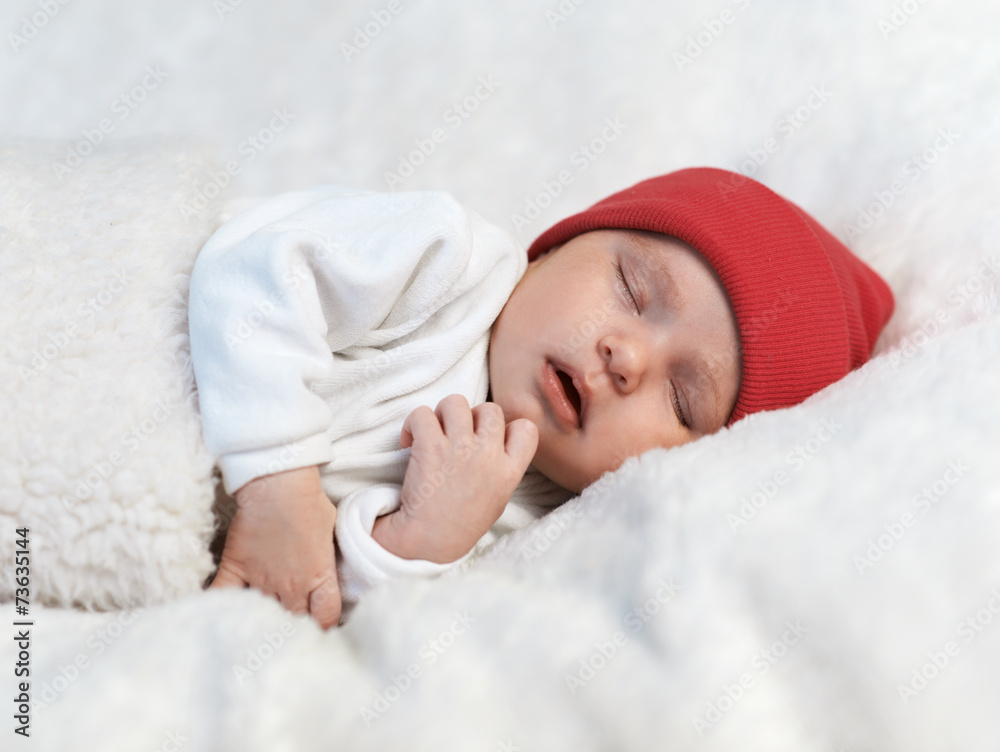 baby sleeping in a red cap on white baby sleeping in a red cap on white