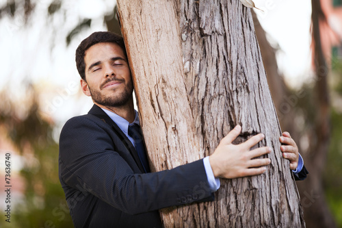 Obraz na plátně Businessman embrace a tree trunk