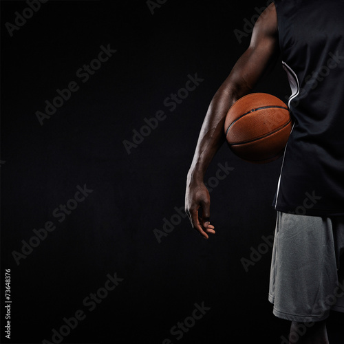 Black basketball player standing with a basket ball © Jacob Lund