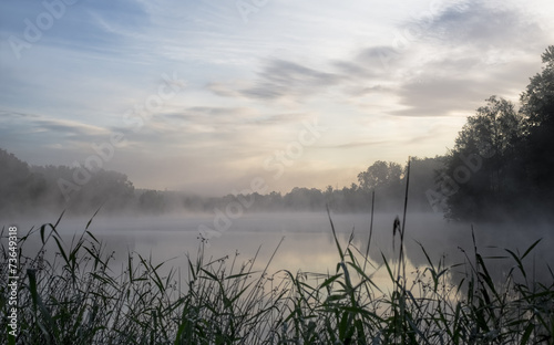 Lake landscape with clouds illuminated by the rising sun.