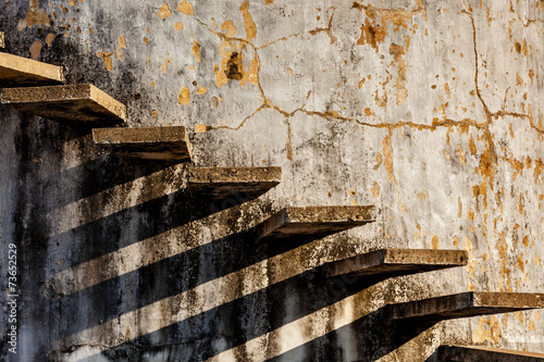 Stairs casting shadow on old weathered wall