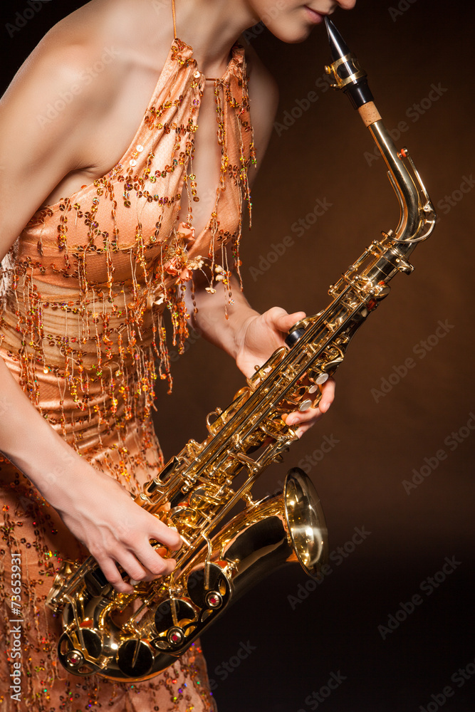 Obraz premium Sexual young woman posing with saxophone at studio