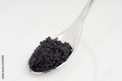 Caviar on a spoon over white plate photo