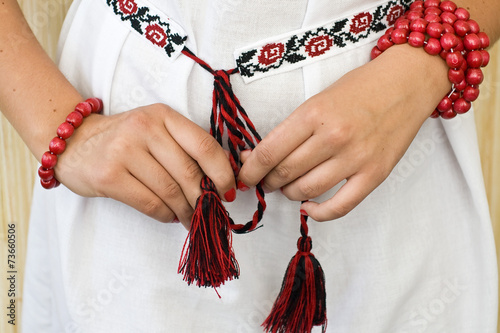 Girl's hands with red bracelets and embroidered shirt