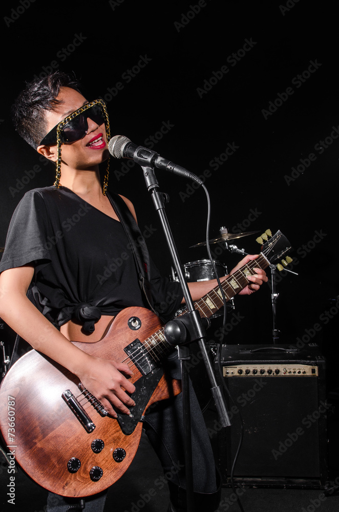 Obraz premium Young woman playing guitar during the concert