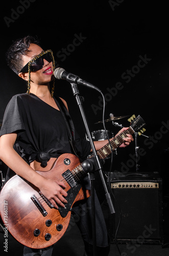 Young woman playing guitar during the concert