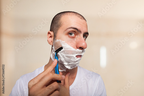 Man using a razor to shave his beard off