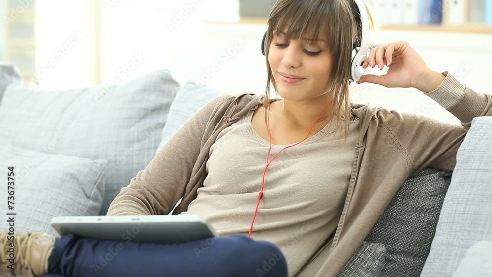 Young woman with headphones websurfing on tablet Young woman with headphones websurfing on tablet