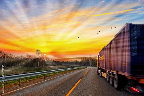 Truck traveling on road at sunrise