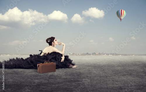 girl in a luxurious dress with a suitcase dreaming