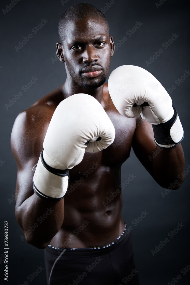Young athletic boxer wearing gloves in black background. Young athletic boxer wearing gloves in black background.