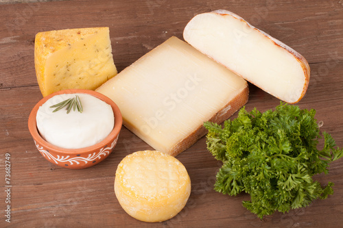 Various types of cheese on a wooden background with parsley