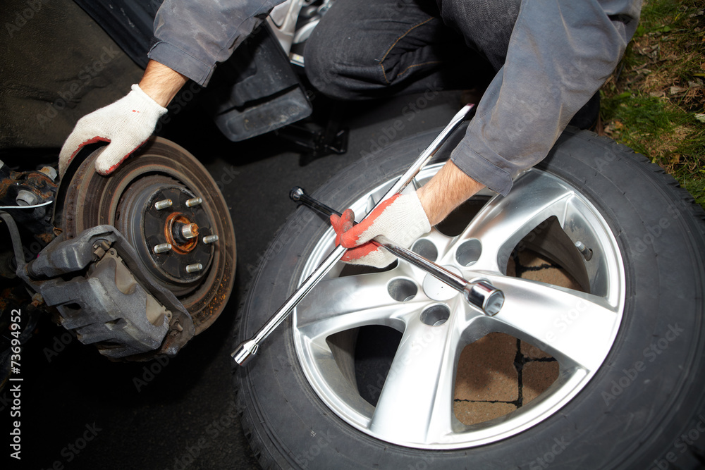 Fototapeta premium Car mechanic changing tire.