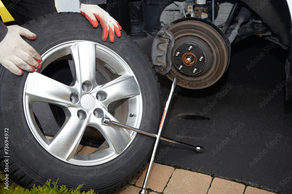 Fototapeta premium Car mechanic changing tire.