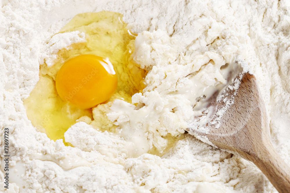Breaking eggs into flour to make bread dough Breaking eggs into flour to make bread dough