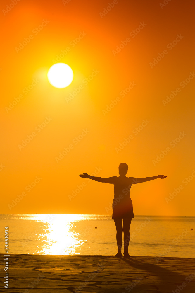 silhouette of woman practicing yoga on the sunset