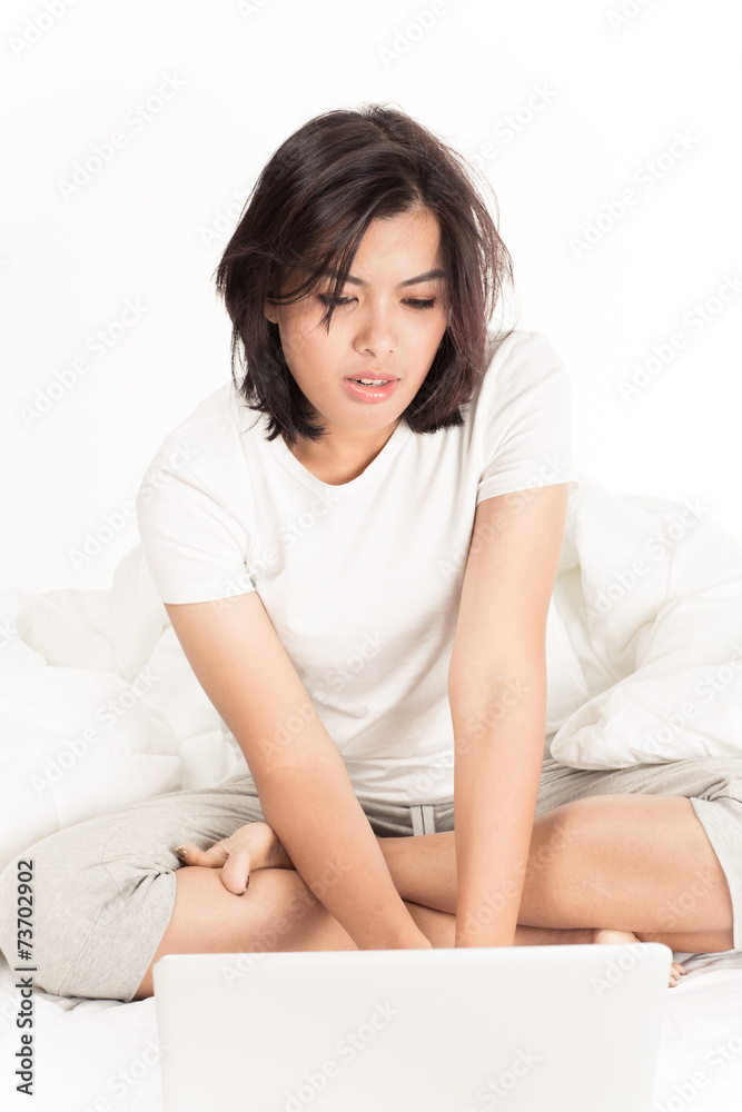 Smiling woman using a laptop while lying on her bed Smiling woman using a laptop while lying on her bed