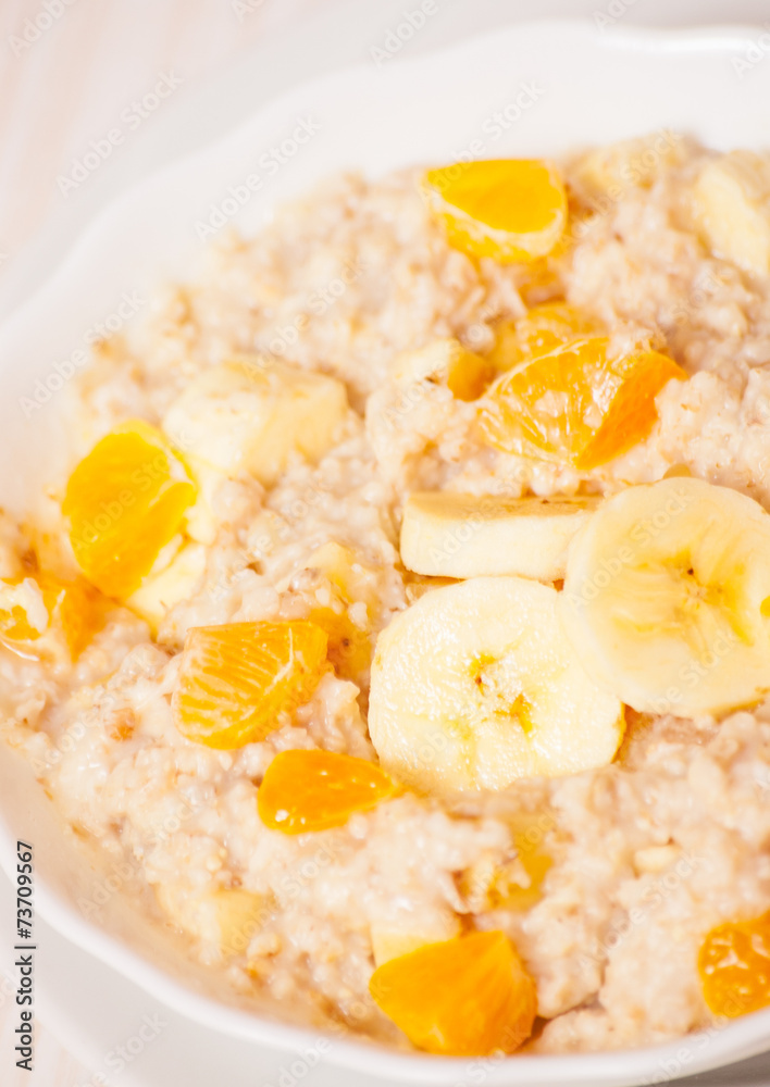 Bowl of oats porridge with banana and tangerine