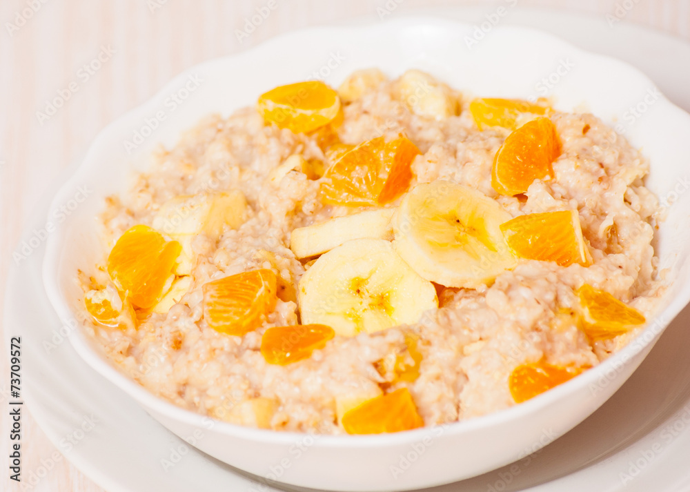 Bowl of oats porridge with banana and tangerine Bowl of oats porridge with banana and tangerine