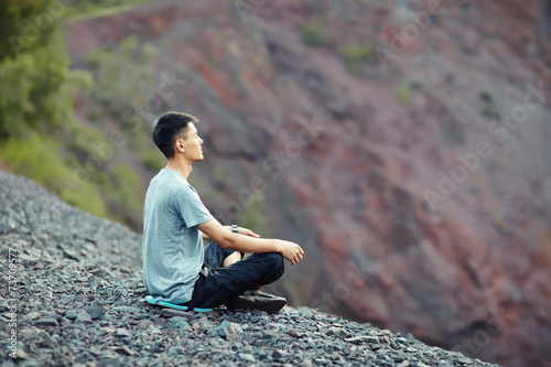 Young man relaxing on rocky cliff