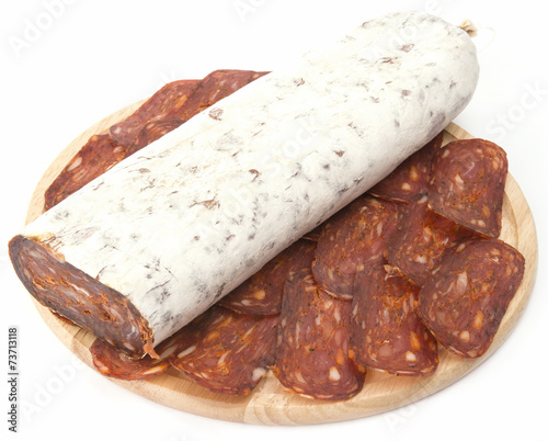 flat sausage on rounder wooden board isolated photo