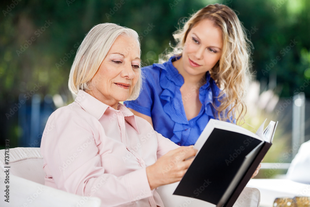Granddaughter Looking At Grandmother Reading Book Granddaughter Looking At Grandmother Reading Book