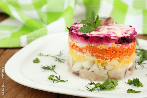 Russian herring salad on plate on wooden table background