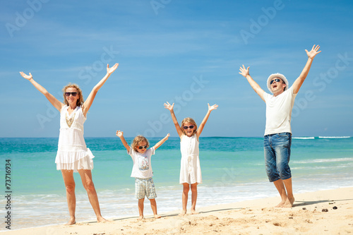 Happy family jumping on the beach on the day time