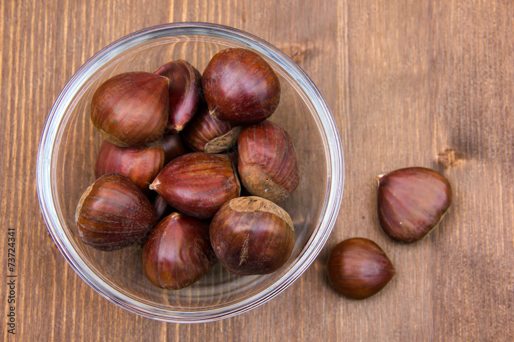 Glass bowl with chestnuts on wooden table top view Glass bowl with chestnuts on wooden table top view