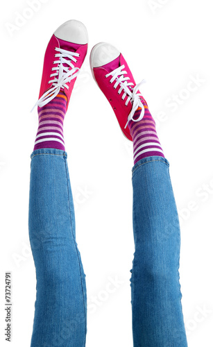 Female legs in colorful socks and sneakers isolated on white