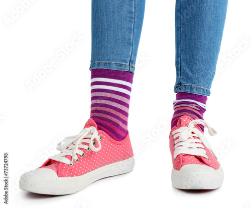 Female legs in colorful socks and sneakers isolated on white