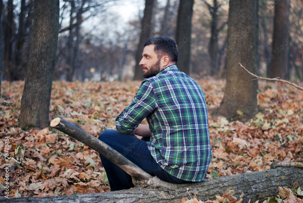 Man sitting on a log in the woods Man sitting on a log in the woods
