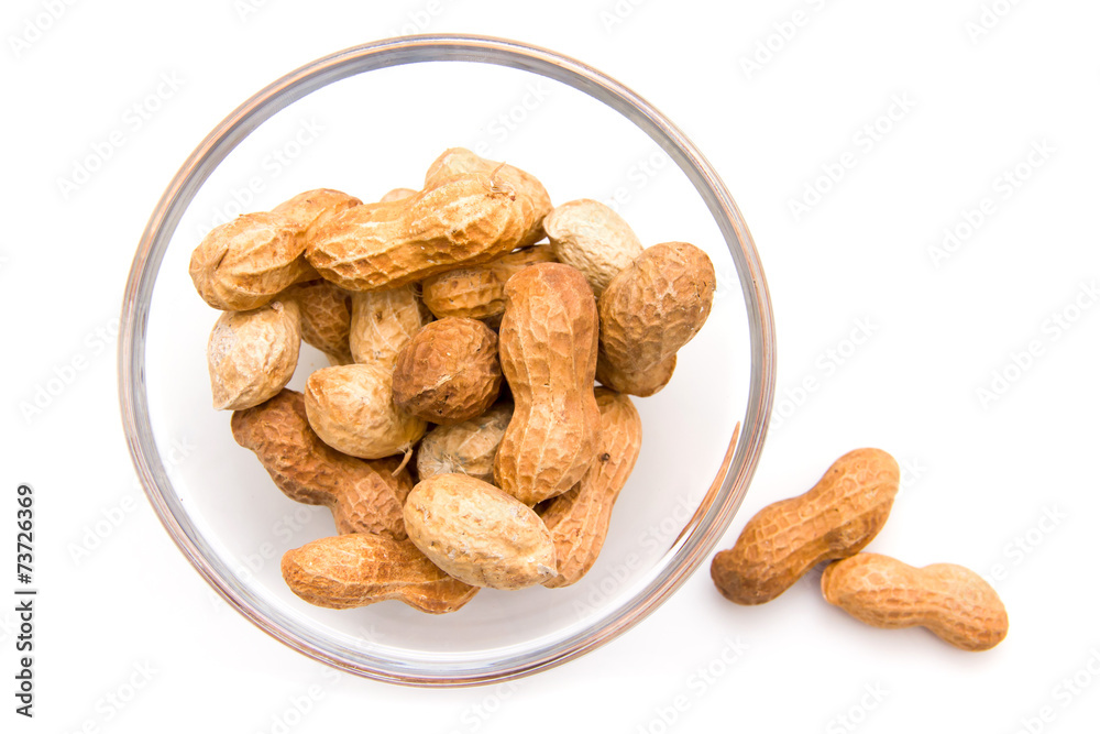 Fototapeta premium Peanuts on glass bowl on white background top view