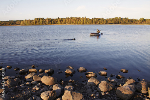 The hunter by the boat in the middle of the lake, to it floats a photo