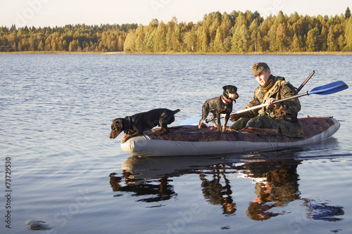 The hunter floats in the boat with two dogs