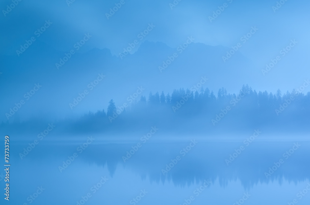 mountains and forest by Barmsee lake in fog