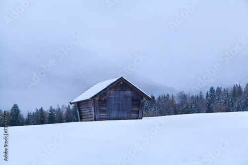 old wooden hut in snowy meadow in Alps