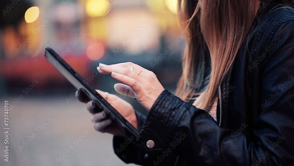 Female hands browsing on tablet in the city night