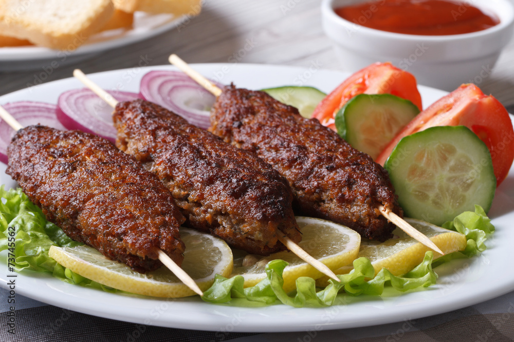 kebabs on wooden skewers and fresh vegetables on a plate