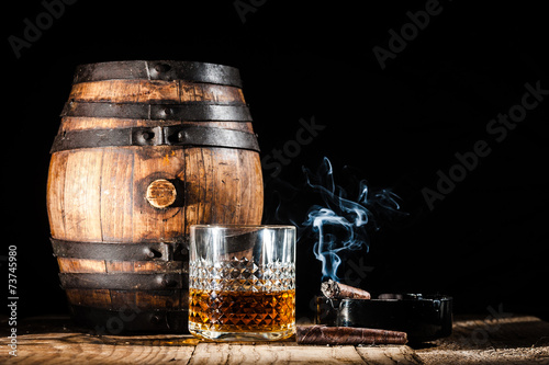 Canvas Print Glass of alcohol and smoking noble cigar on a black background