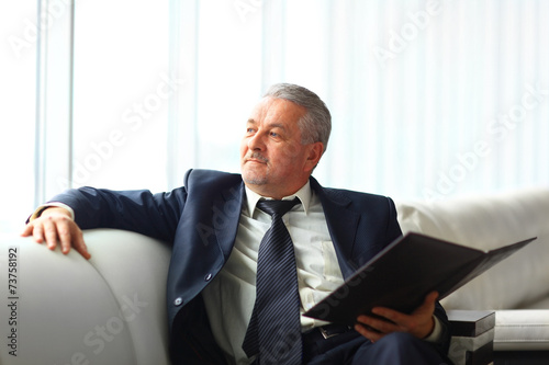 businessman in office with a folder sits and works