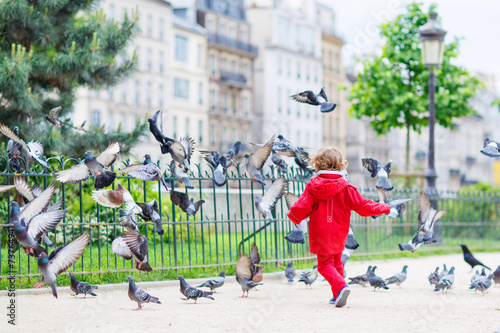 Cute little  boy catching and playing with pigeons in city photo