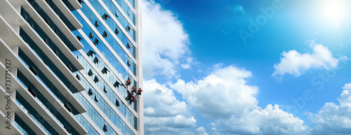Group of workers cleaning windows on high rise building photo