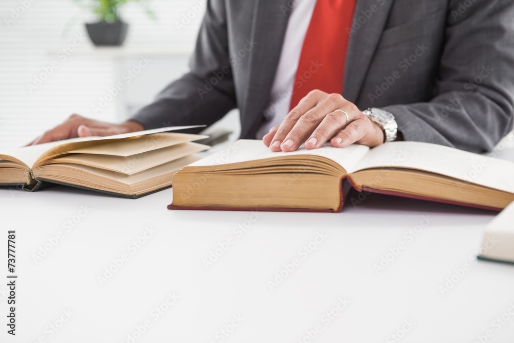 Businessman sitting at desk reading books Businessman sitting at desk reading books