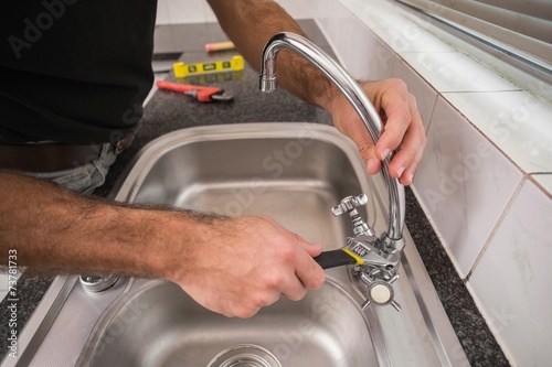 Plumber fixing the sink with wrench photo