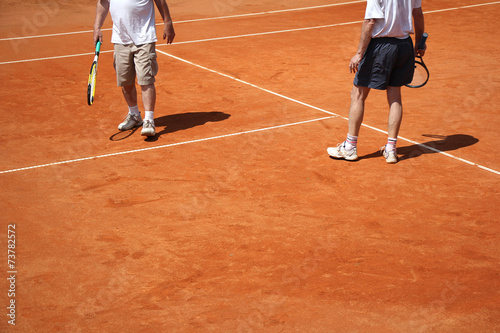 Male couple playing tennis on the court on a sunny day