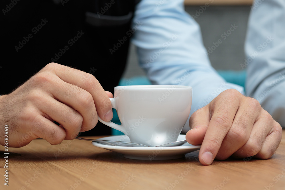 Junger Mann hält Kaffeetasse auf Holztisch Junger Mann hält Kaffeetasse auf Holztisch