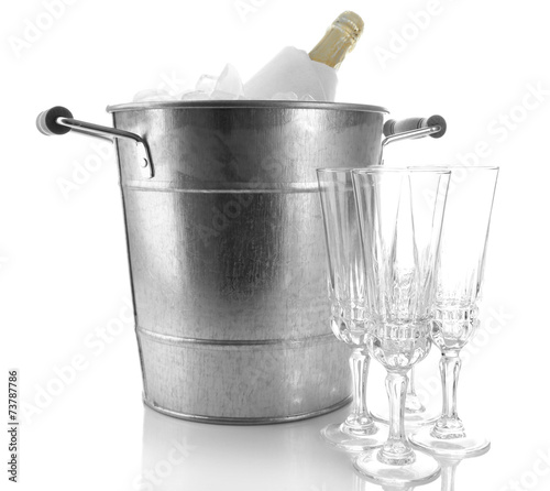 Bottle of champagne in metal ice bucket and empty glasses