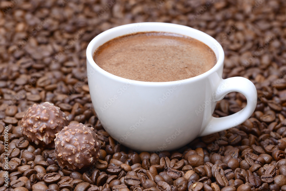 cup of coffee and candies on a coffee beans background cup of coffee and candies on a coffee beans background