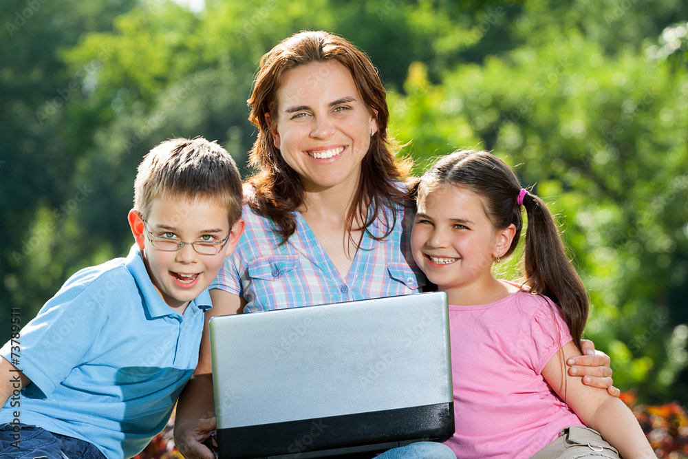 Happy Family using laptop lying on grass Happy Family using laptop lying on grass